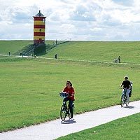 Cyclists in front of Pilsum lighthouse in East Frisia